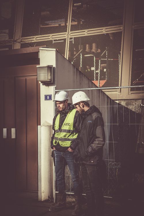 Foto van bouwvakkers met veiligheidshelmen en -vesten in een hoog-risico werkomgeving